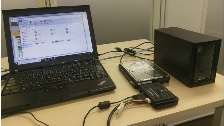 机の上のパソコンにUSBとSATAケーブルでHDDを繋いでいる