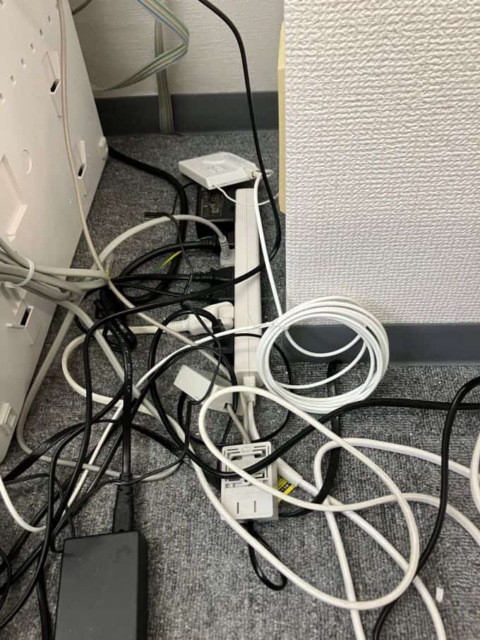 電源タップの周りに複雑に絡み合ったLANケーブルや電源コード